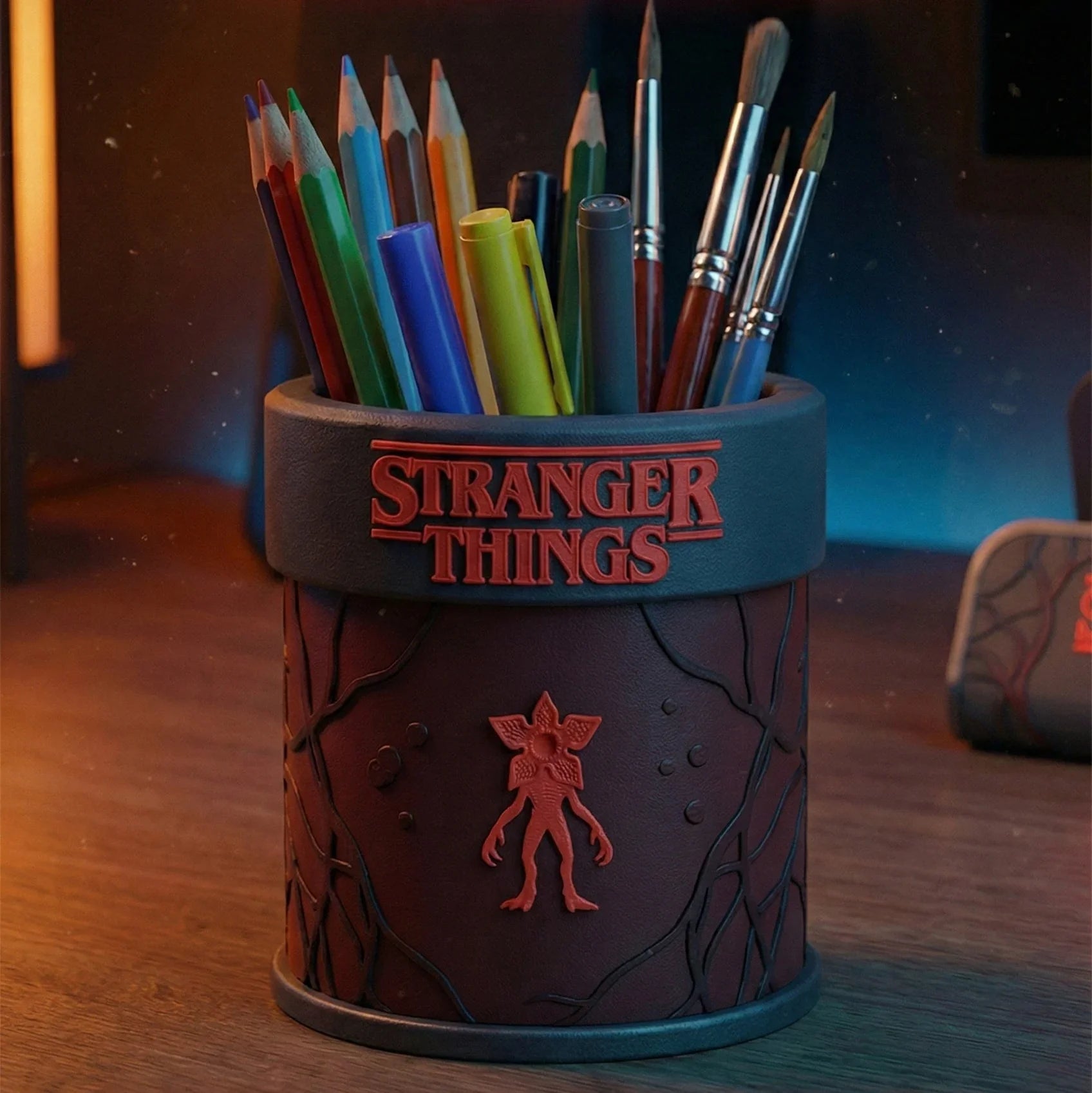 Stranger Things themed desk organizer holding colored pencils and brushes on a wooden workspace.