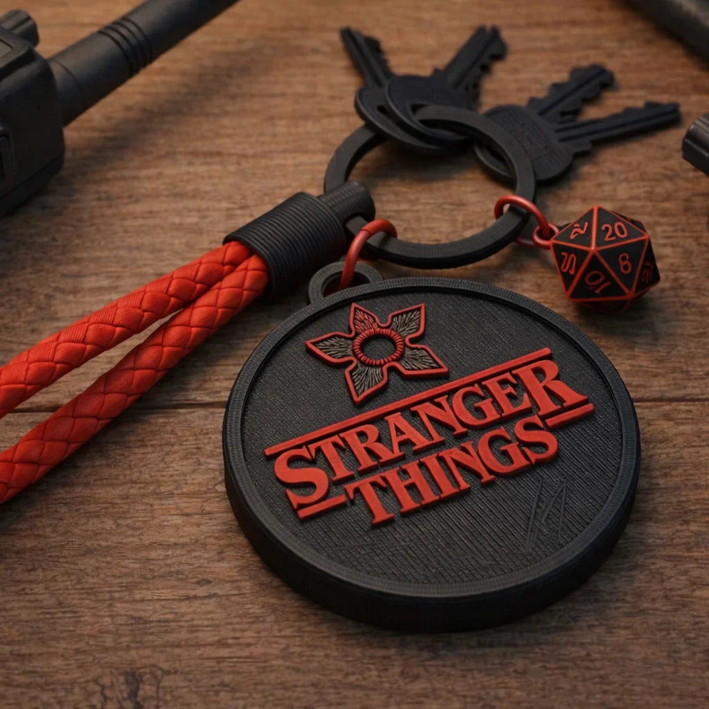 Stranger Things keychain with red braided lanyard and D20 dice on wood desk surface