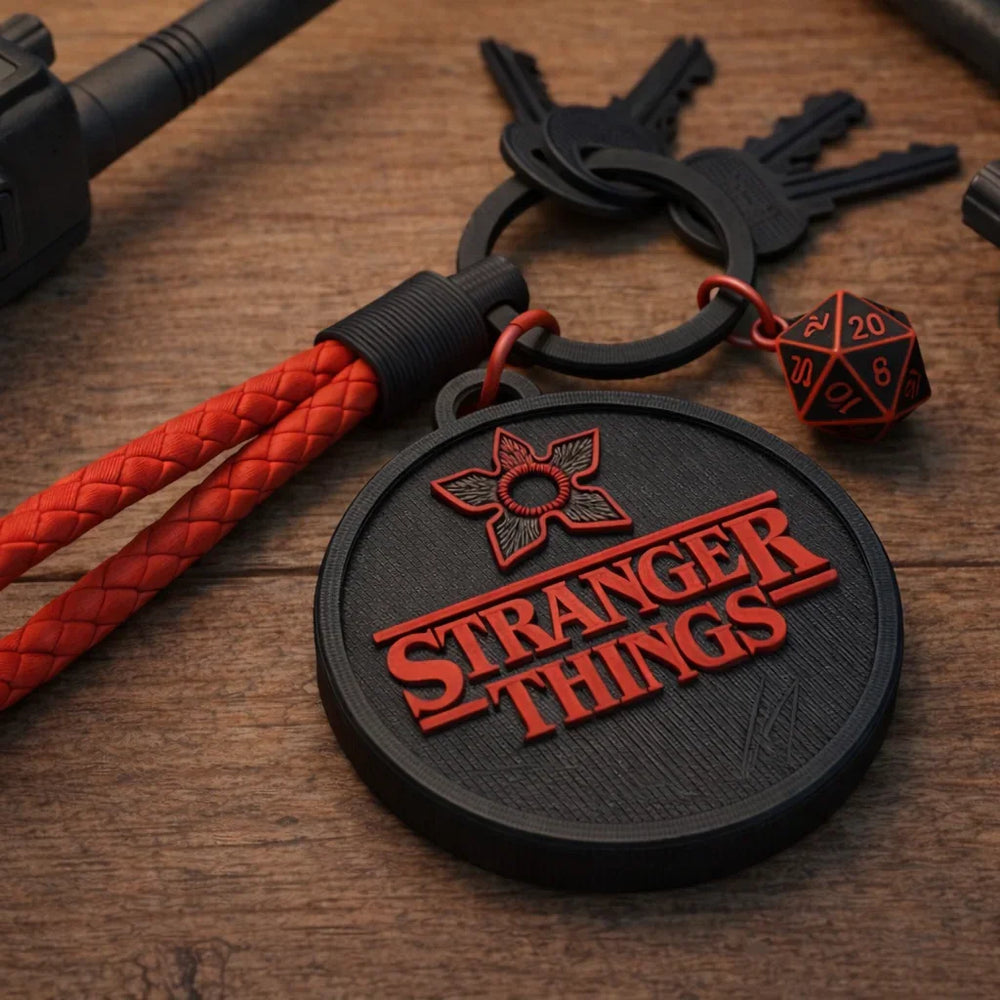 Stranger Things keychain with red braided lanyard and D20 dice on wood desk surface