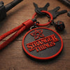 Stranger Things keychain with braided red strap and d20 dice on wooden desk